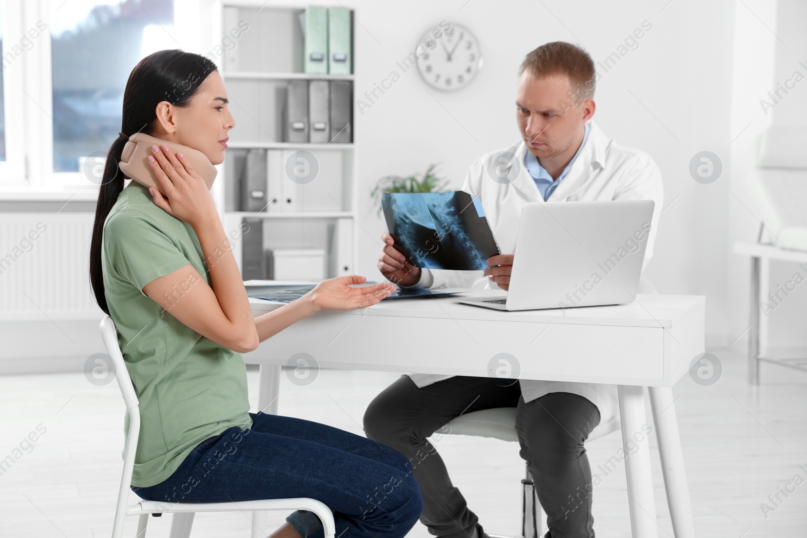 Photo of Doctor with neck MRI image consulting patient in clinic