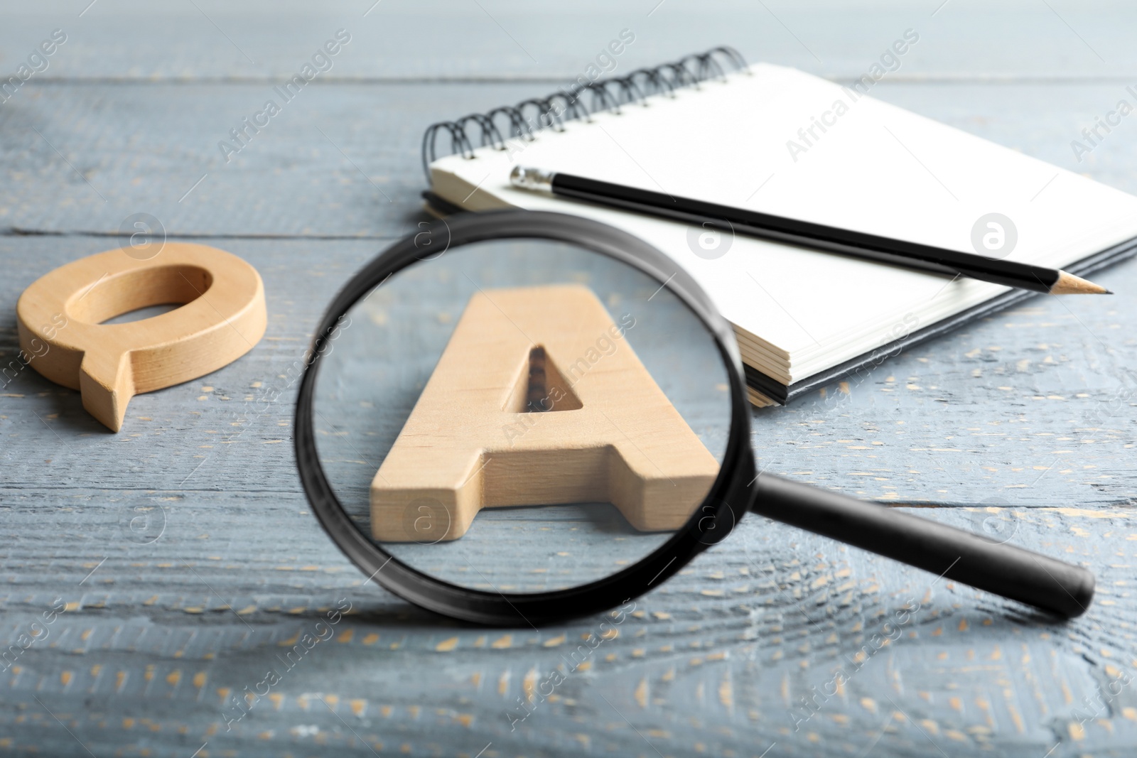 Photo of Magnifier glass, letters and notebook with pencil on light grey wooden table, closeup. Find keywords concept