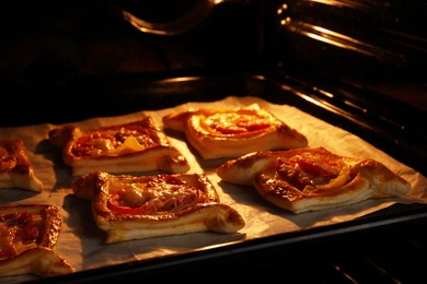 Baking sheet of puff pastry with tasty filling in oven, closeup