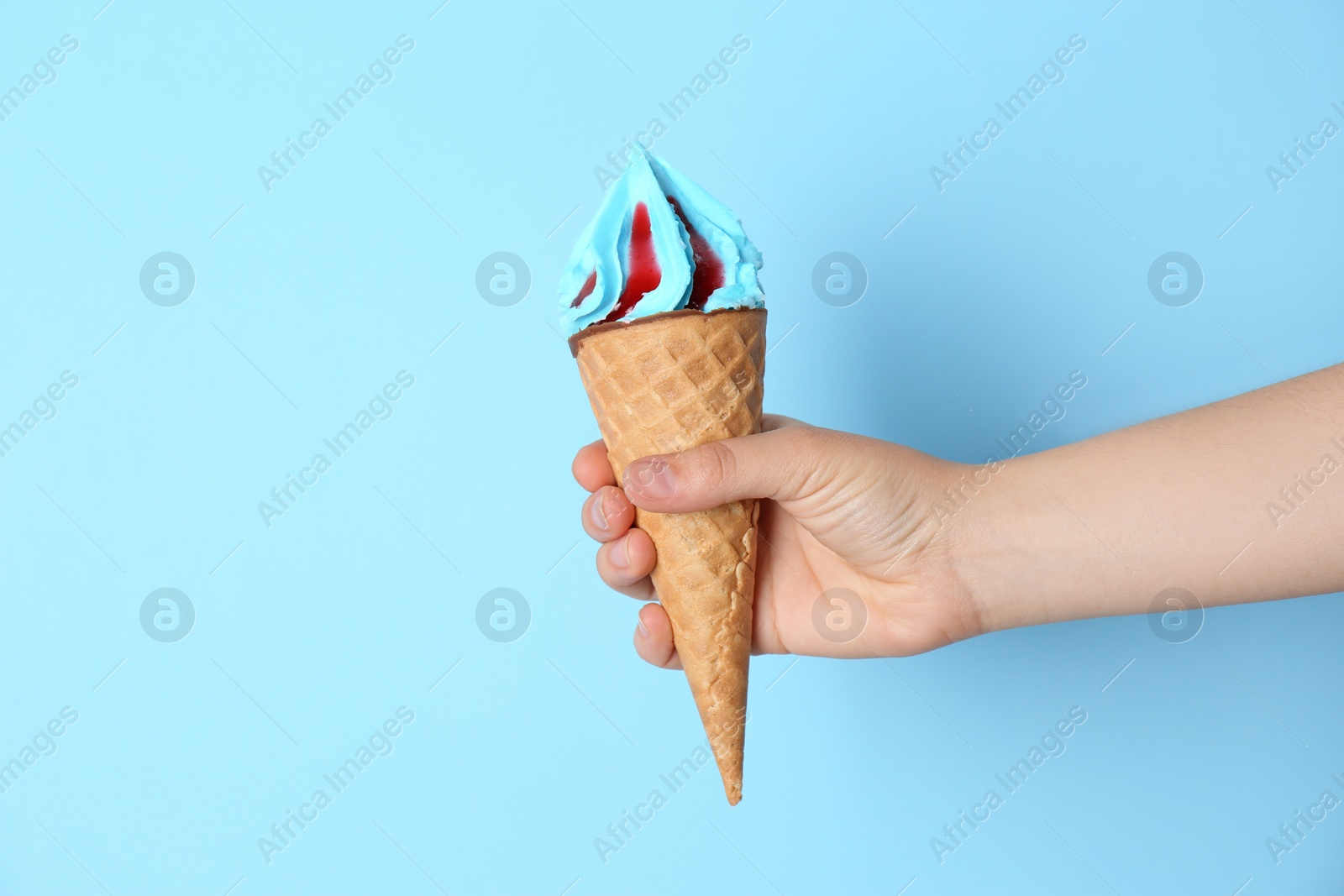 Photo of Woman holding waffle cone with delicious ice cream on color background