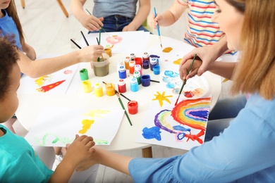 Photo of Female teacher with children at painting lesson indoors