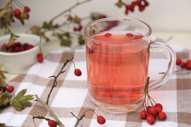 Photo of Cup with hawthorn tea and berries on table, closeup. Space for text