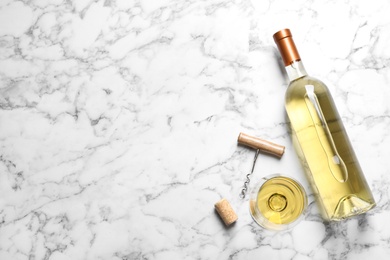 Glass and bottle with white wine on marble background, flat lay. Space for text