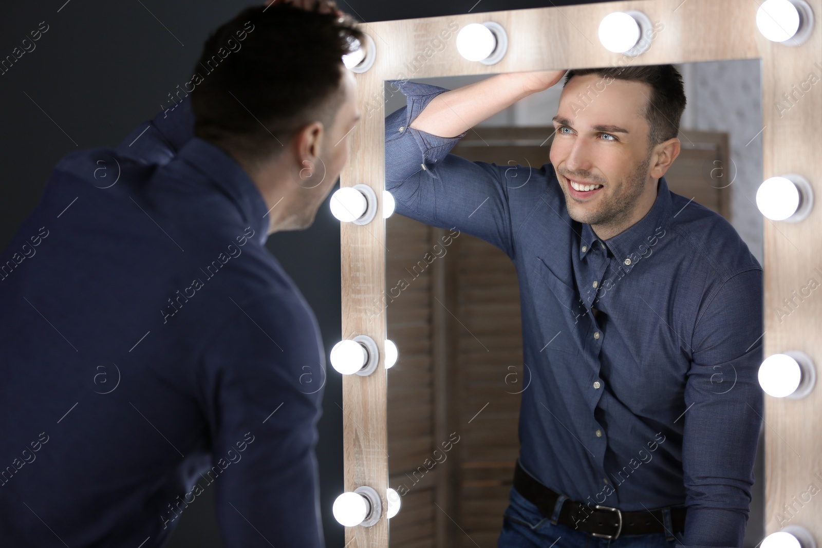 Photo of Young man looking at himself in mirror