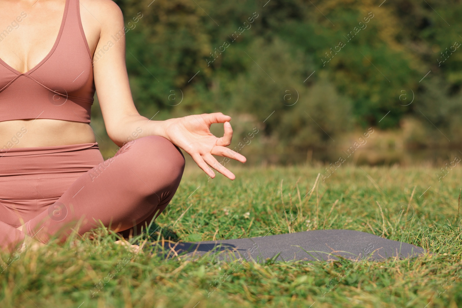 Photo of Woman practicing yoga on mat outdoors, closeup and space for text. Lotus pose