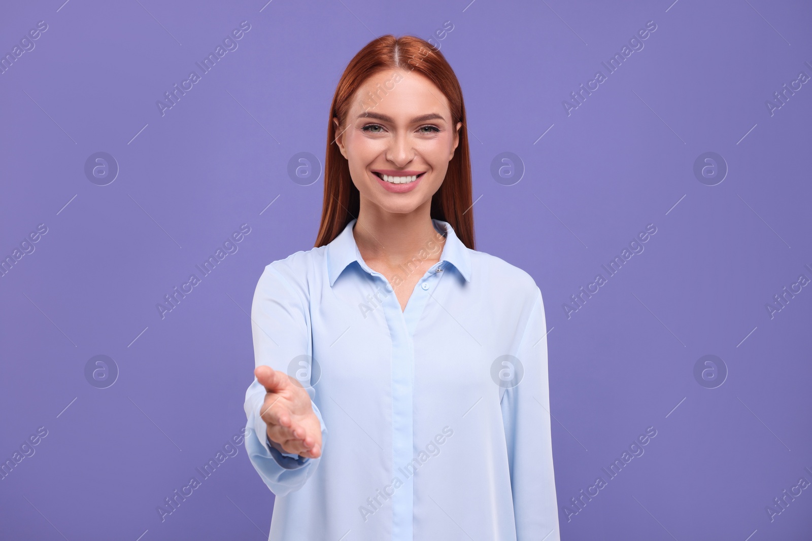 Photo of Happy woman welcoming and offering handshake on violet background