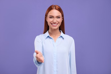 Photo of Happy woman welcoming and offering handshake on violet background