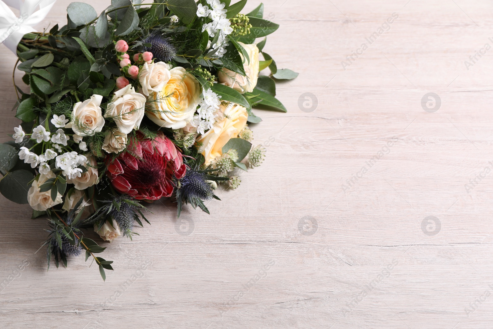 Photo of Beautiful bouquet with roses on white wooden background. Space for text