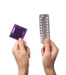 Young woman holding birth control pills and condom on white background, closeup. Safe sex concept