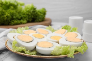 Photo of Fresh hard boiled eggs and lettuce on white marble table