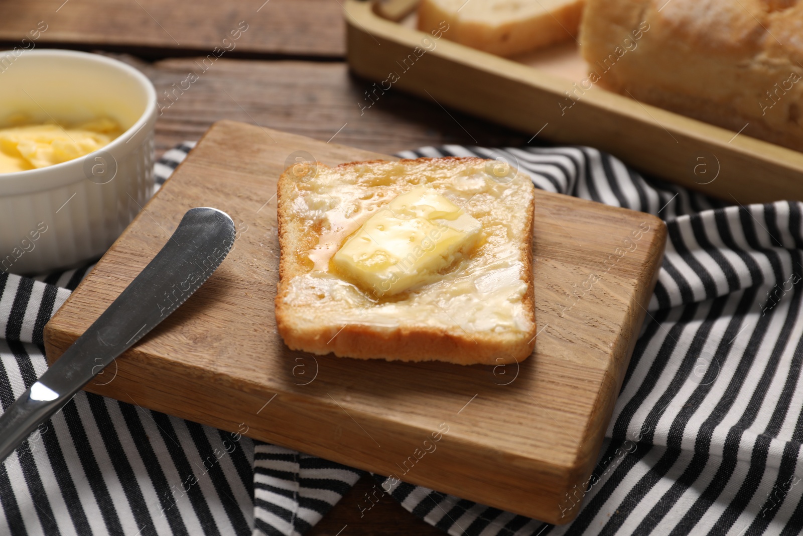 Photo of Melting butter, toast and knife on wooden table, closeup