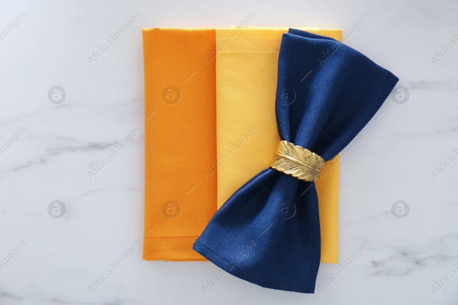 Photo of Colorful napkins and decorative ring on white marble table, top view