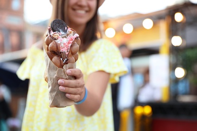 Young woman holding delicious sweet bubble waffle with ice cream outdoors, closeup