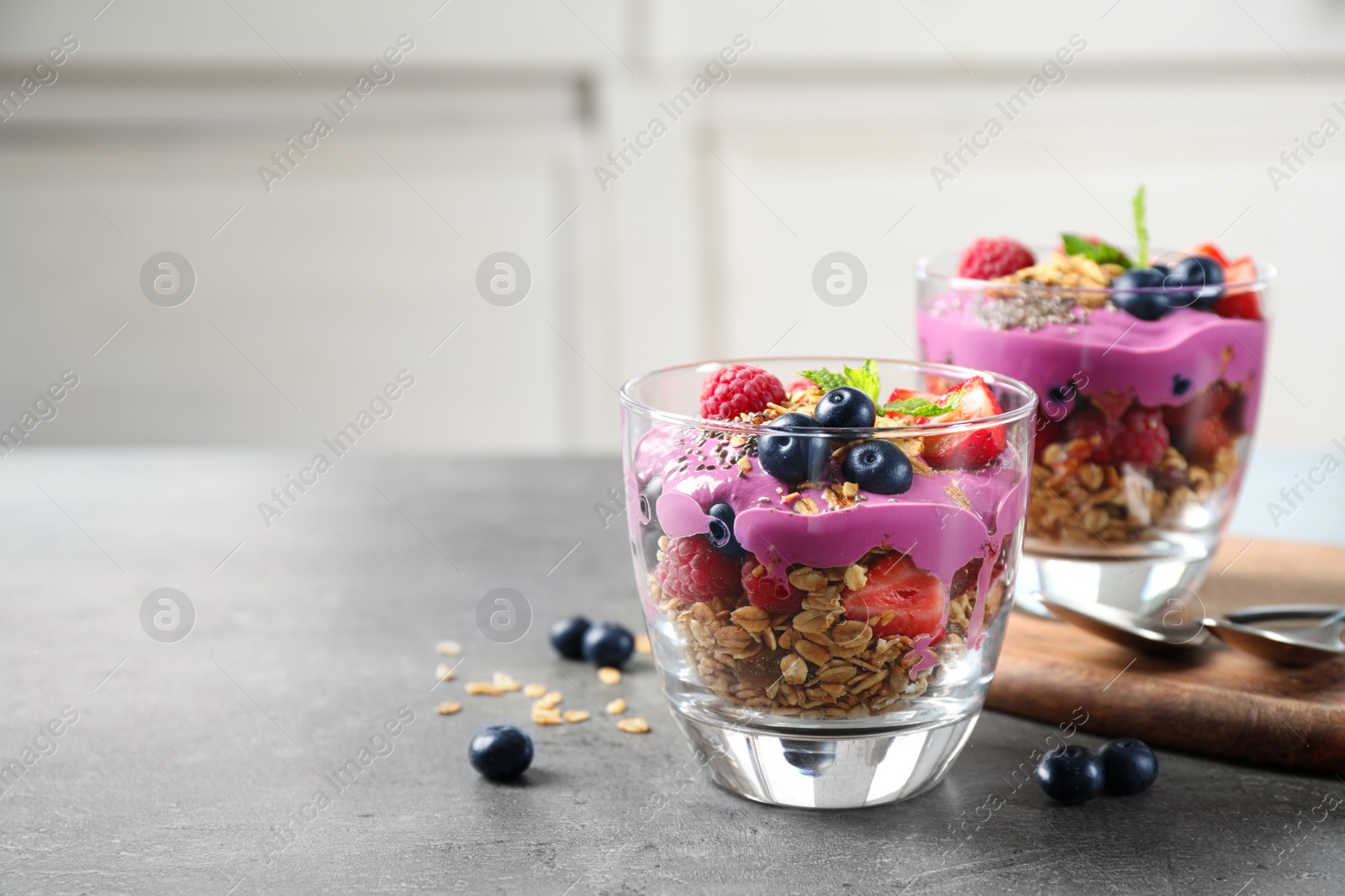 Image of Tasty dessert with acai smoothie, granola and berries on grey table. Space for text