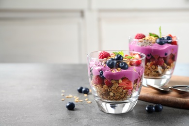 Tasty dessert with acai smoothie, granola and berries on grey table. Space for text