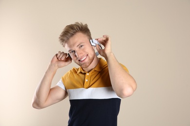 Photo of Handsome young man listening to music with headphones on color background