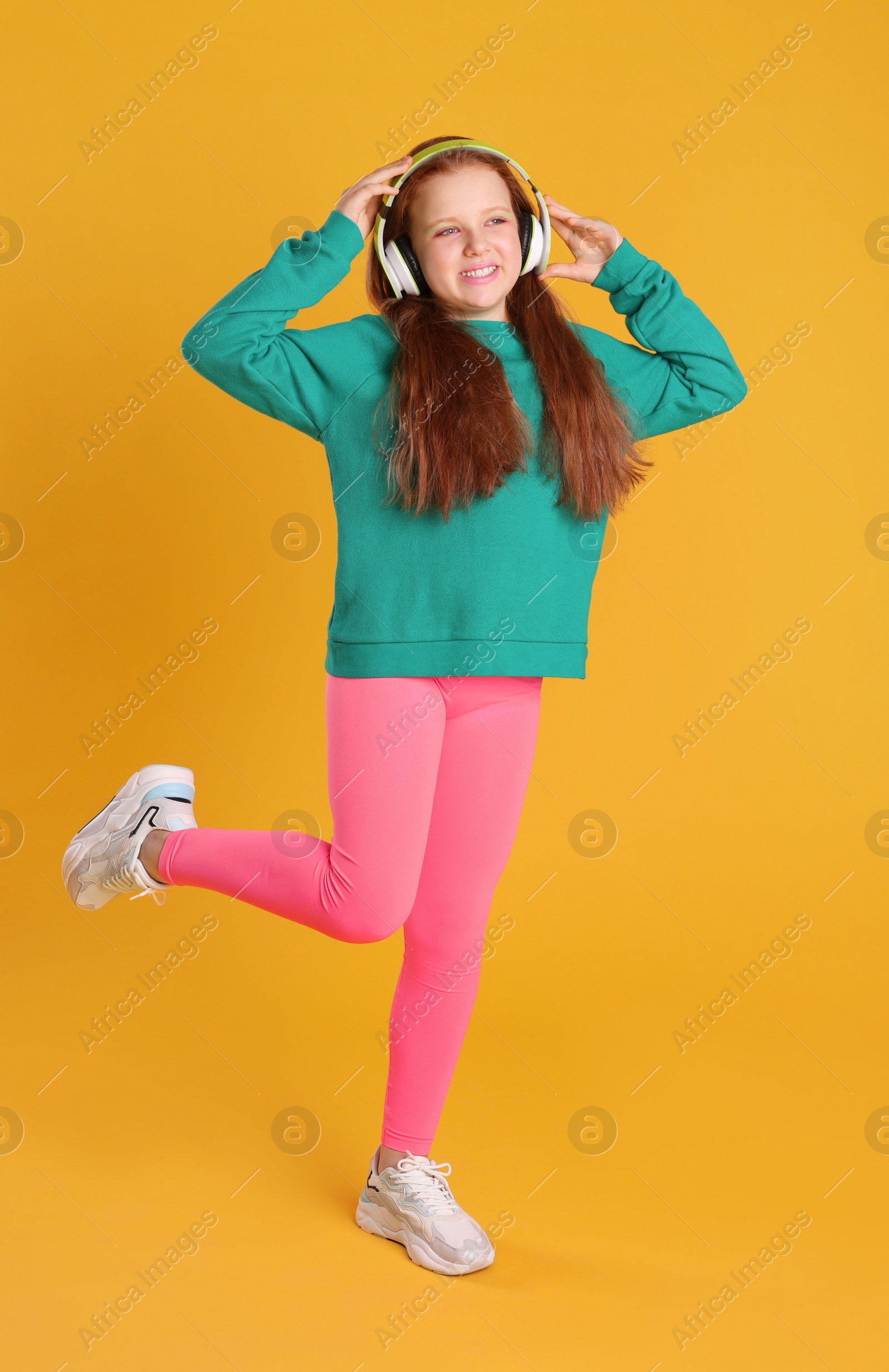 Photo of Cute indie girl in headphones on yellow background