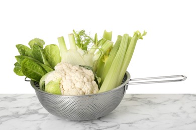 Photo of Metal colander with different vegetables on marble table against white background