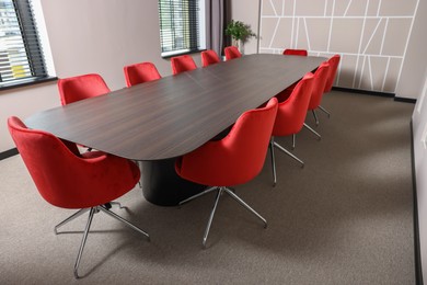 Empty conference room with stylish red office chairs and large wooden table