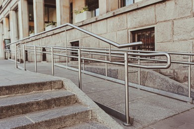 Photo of Tiled ramp with shiny metal railings outdoors