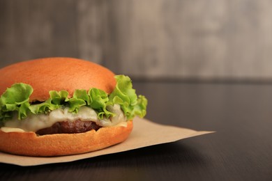 Photo of One tasty cheeseburger on wooden table, closeup. Space for text