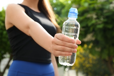 Young woman with bottle of pure water outdoors, closeup
