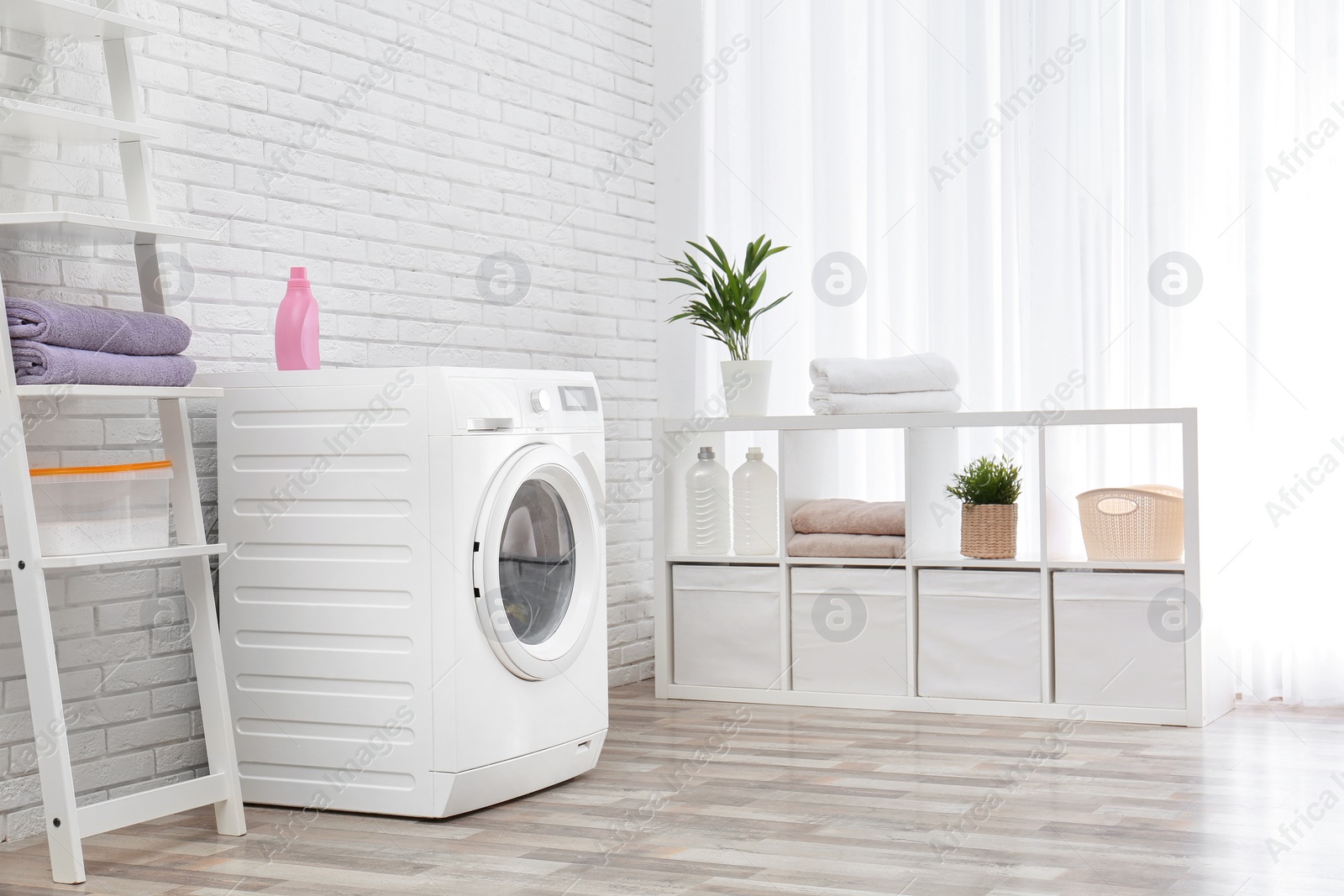 Photo of Modern washing machine near brick wall in laundry room interior