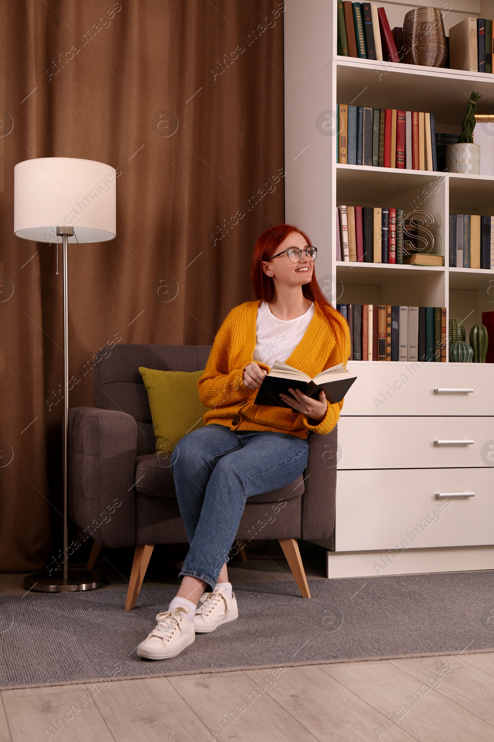 Photo of Beautiful young woman reading book in armchair indoors. Home library