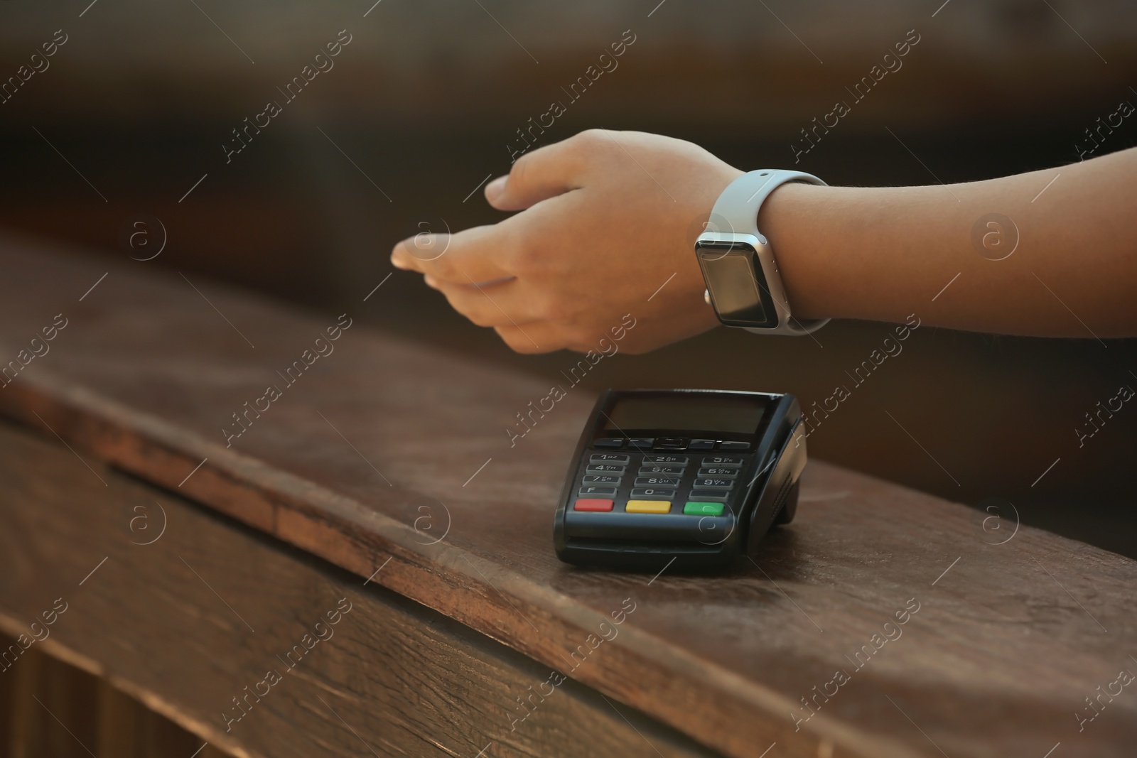 Photo of Woman using terminal for contactless payment with smart watch outdoors