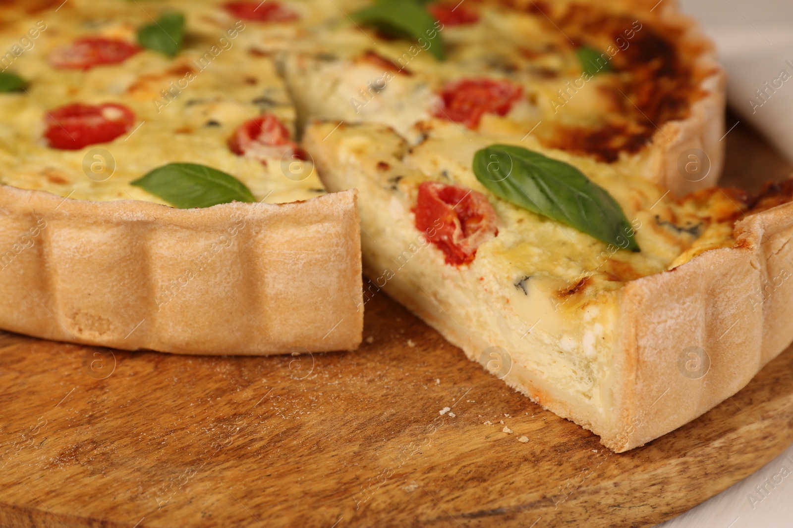 Photo of Delicious homemade cheese quiche on wooden board, closeup