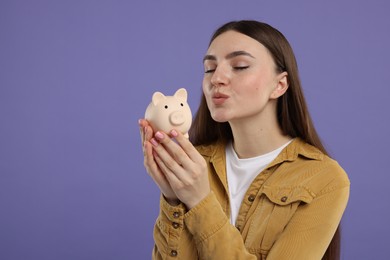 Photo of Woman with piggy bank on purple background, space for text