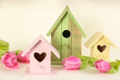 Photo of Beautiful bird houses and tulips on beige background