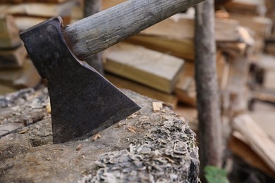 Photo of Ax with wooden handle near log pile, closeup