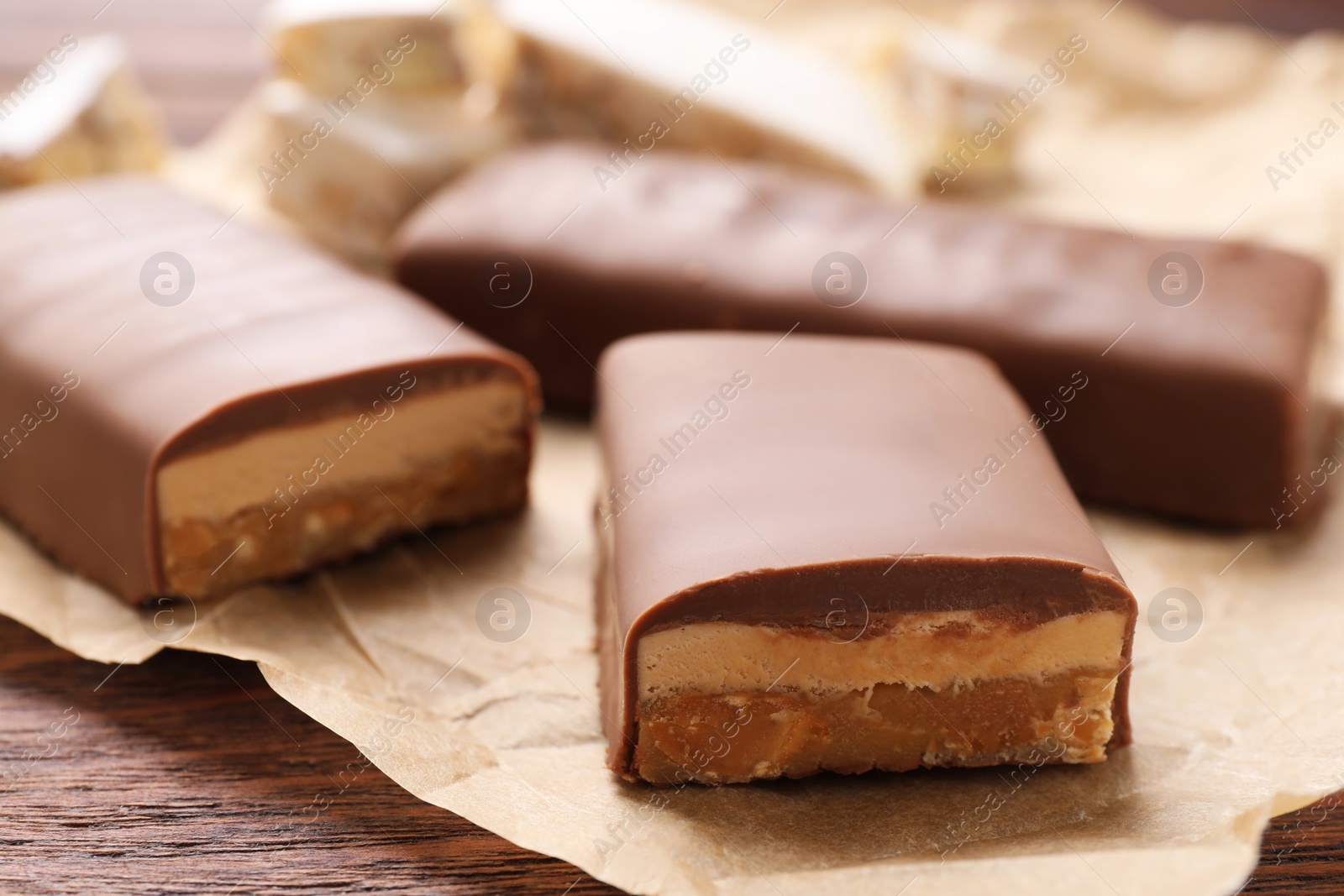 Photo of Pieces of tasty chocolate bars with nougat on table, closeup