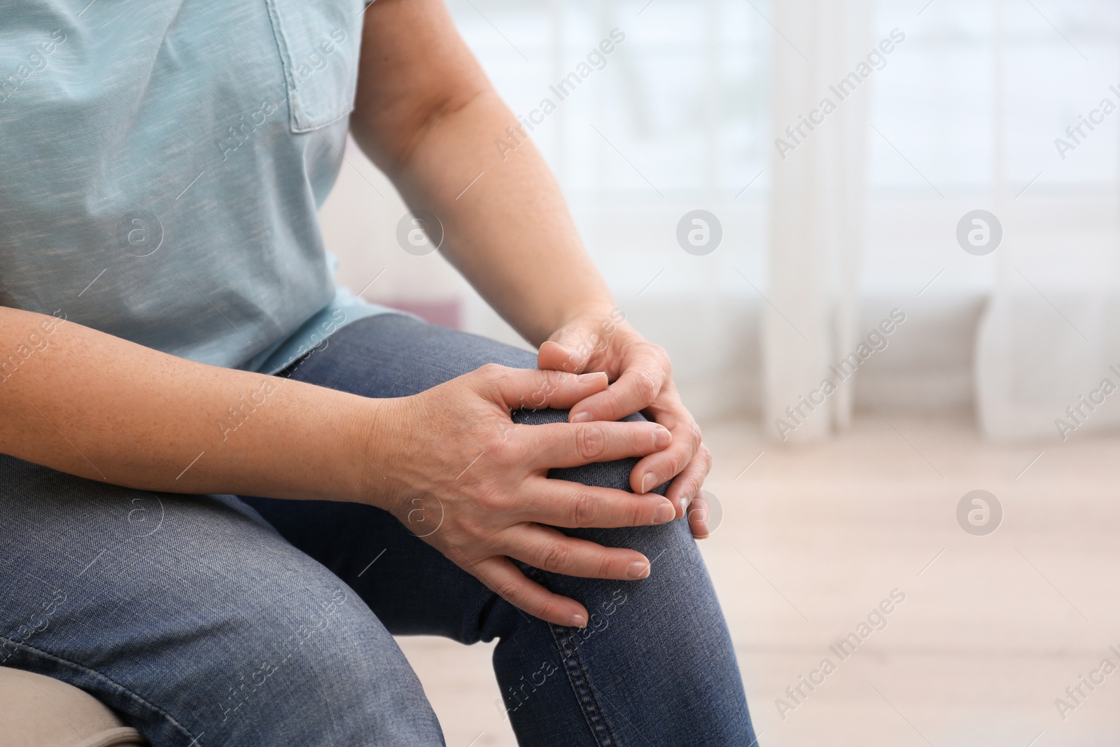 Photo of Senior woman suffering from knee pain at home, closeup. Space for text