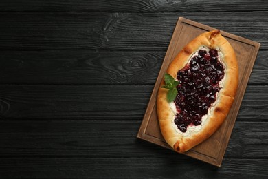 Delicious sweet cottage cheese pastry with cherry jam on black wooden table, top view. Space for text