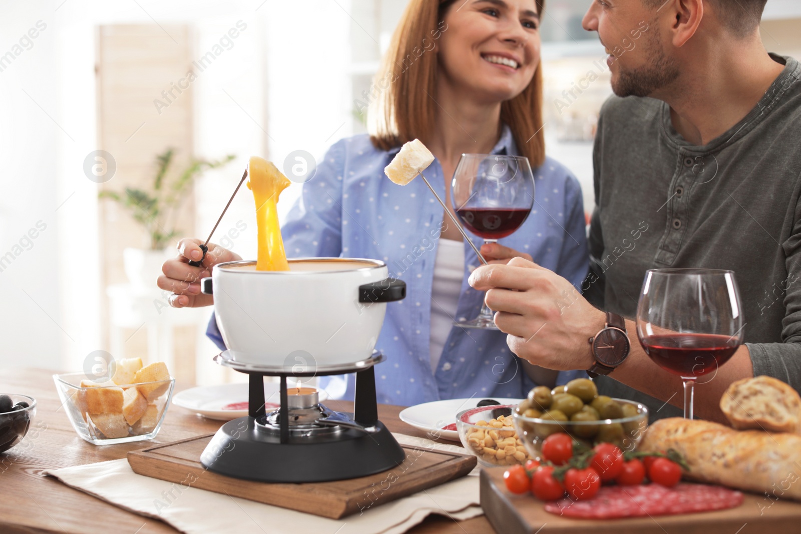 Photo of Happy couple enjoying fondue dinner at home