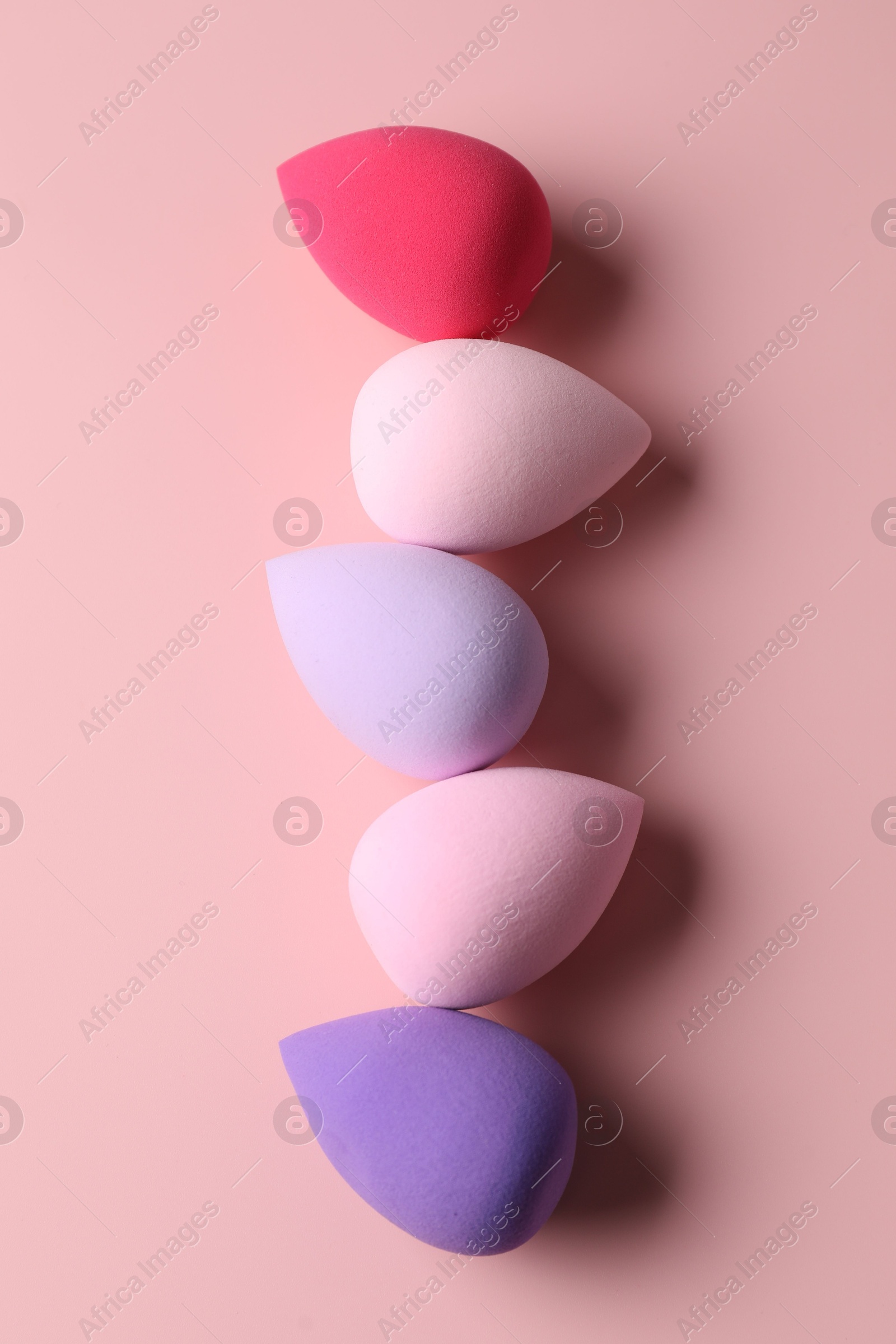 Photo of Many colorful makeup sponges on pink background, flat lay