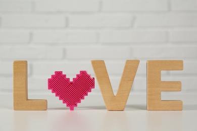 Word Love made of wooden letters and decorative heart on white table