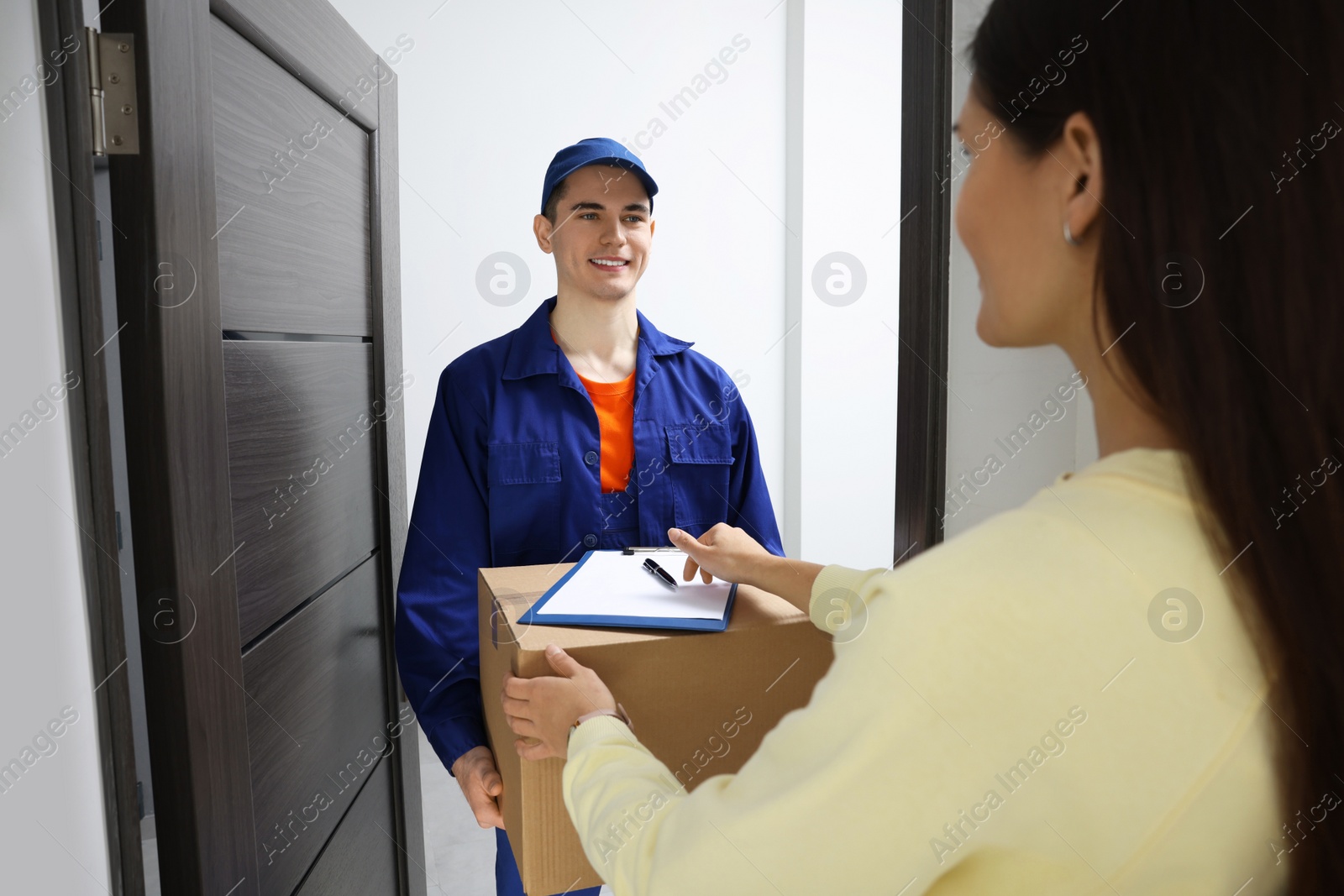 Photo of Woman receiving parcel from courier at home