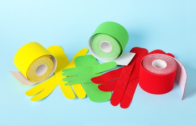 Photo of Bright kinesio tape rolls and pieces on light blue background