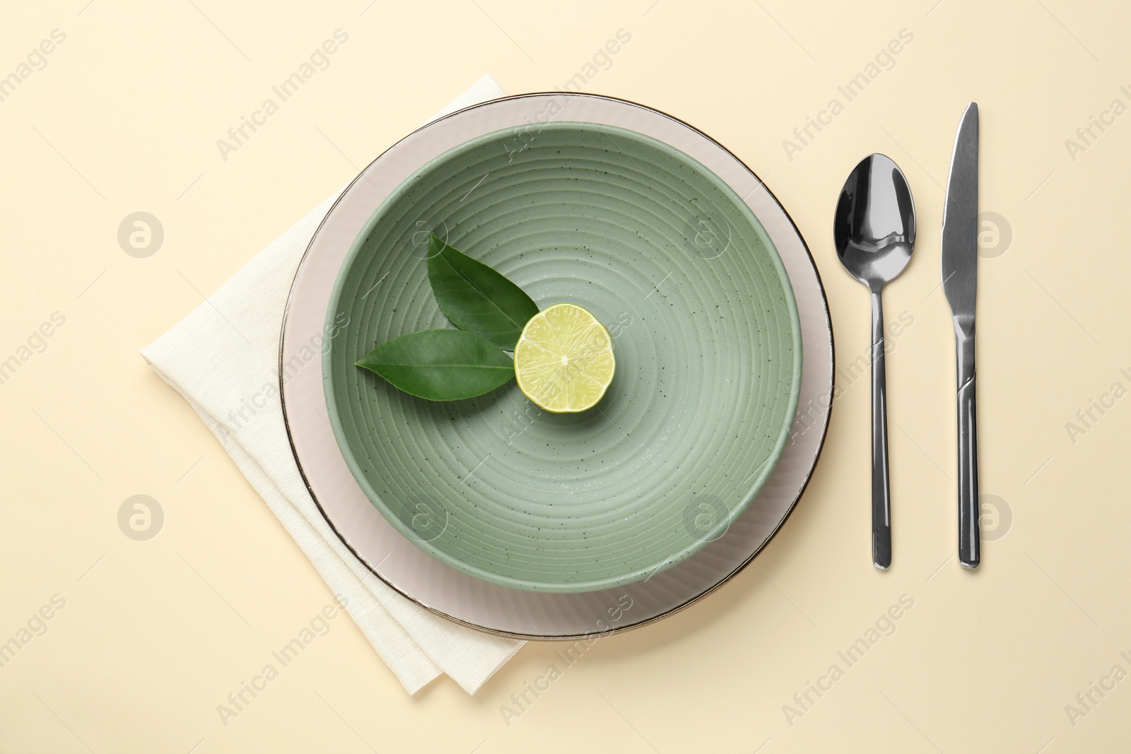Photo of Stylish ceramic plate, bowl, cutlery and decor on beige background, top view