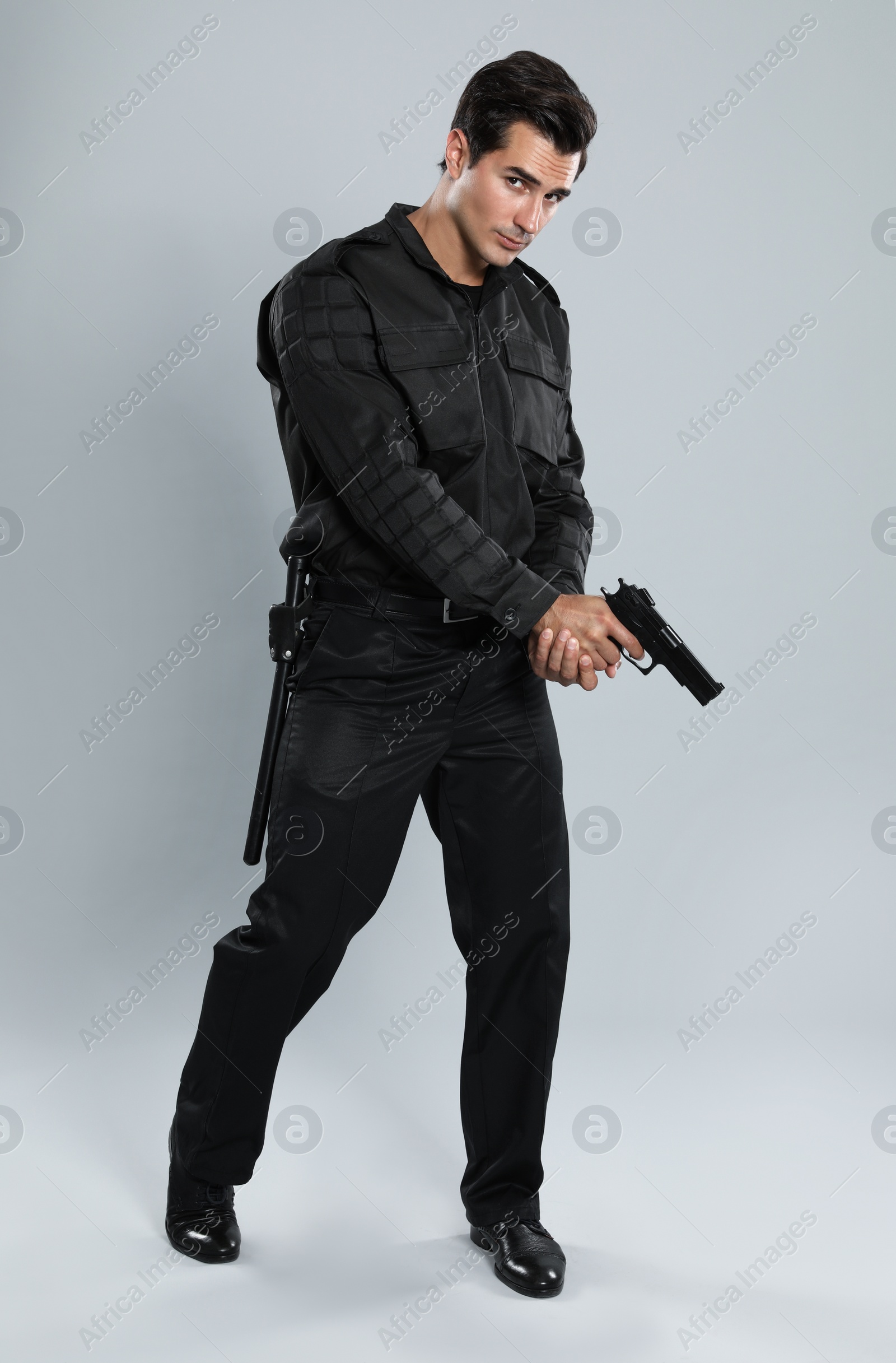 Photo of Male security guard in uniform with gun on grey background