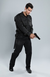 Male security guard in uniform with gun on grey background