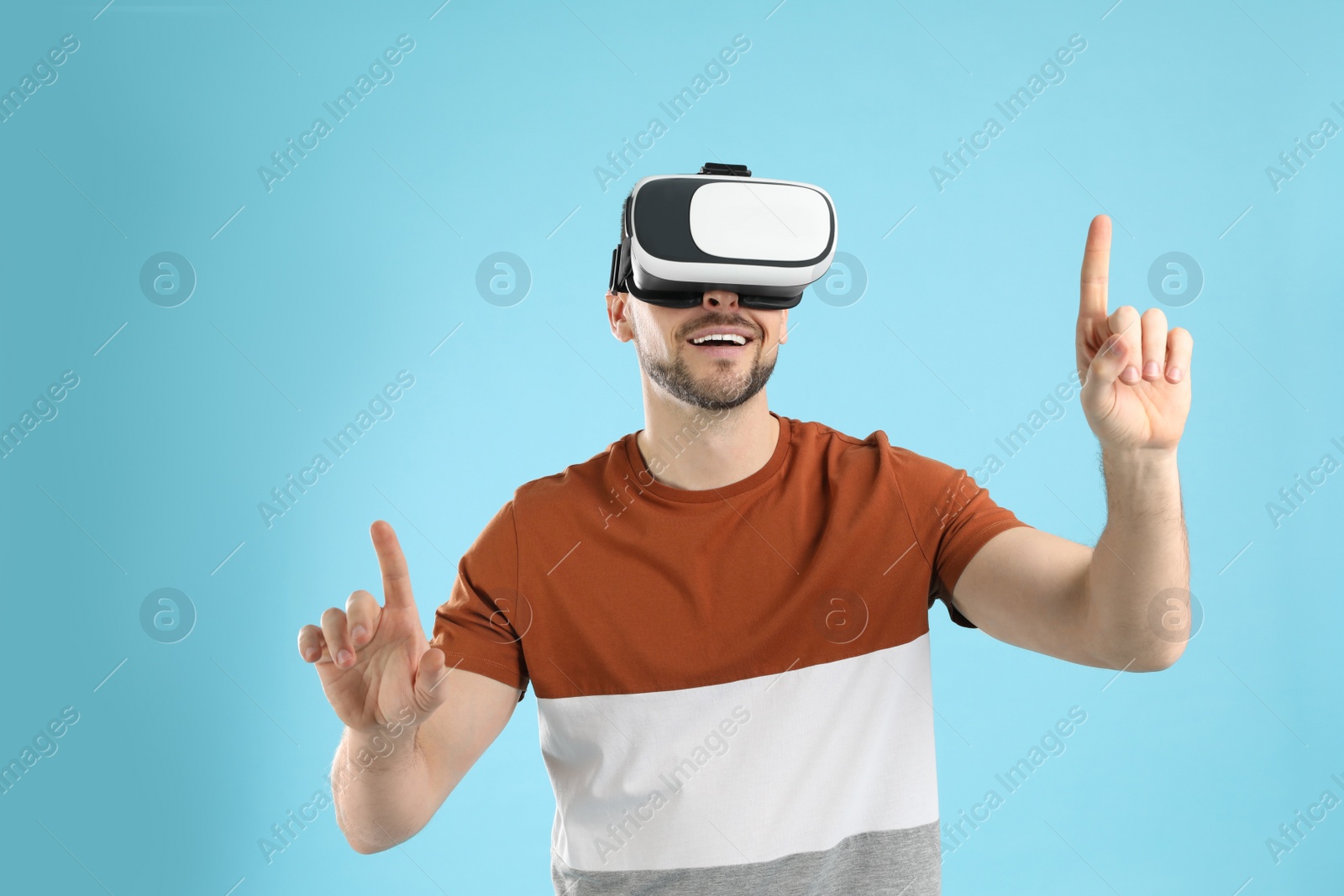 Photo of Man using virtual reality headset on light blue background