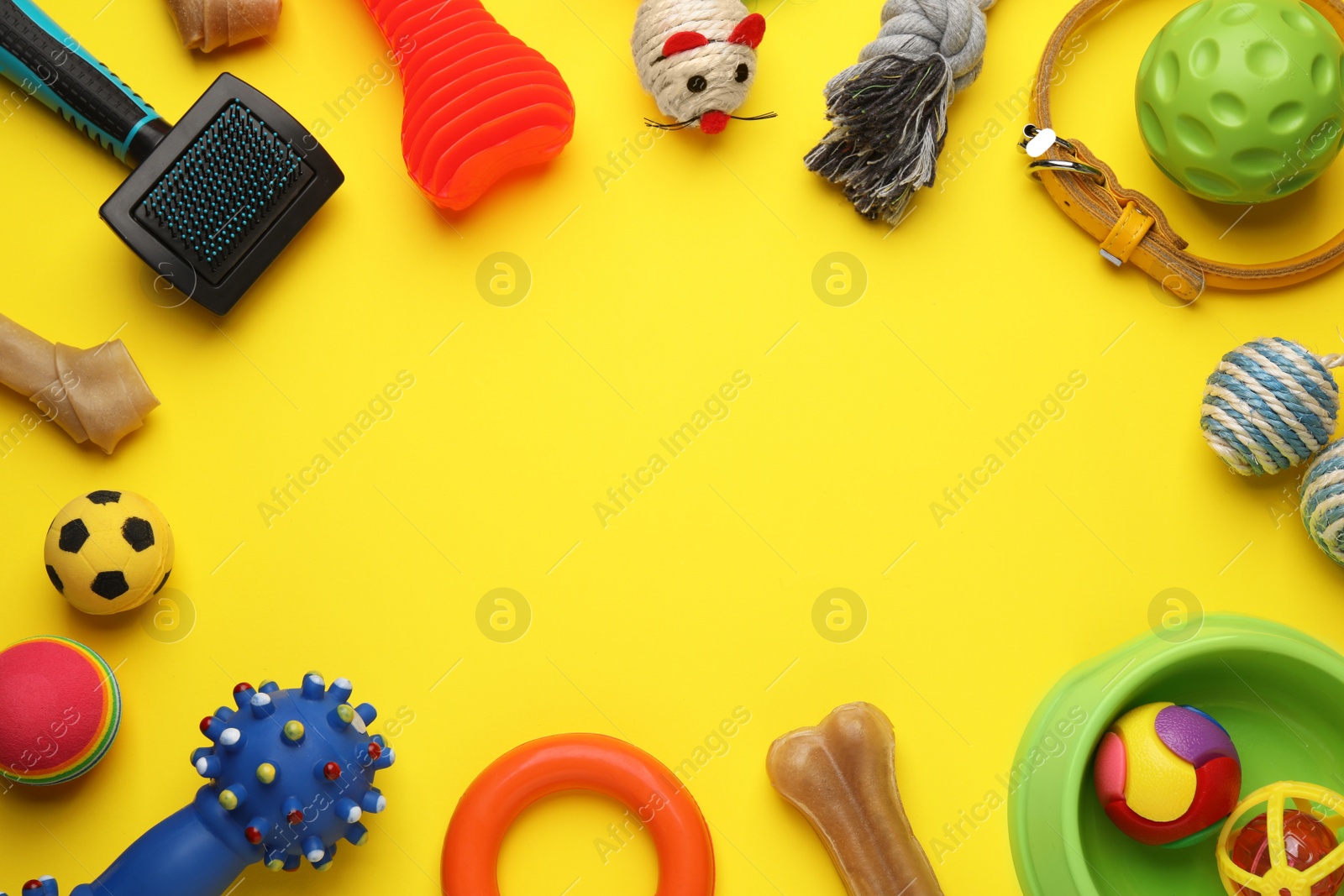 Photo of Frame made with pet toys and feeding bowl on yellow background, flat lay. Space for text