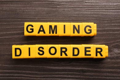 Photo of Phrase Gaming Disorder made of yellow cubes on wooden table, top view