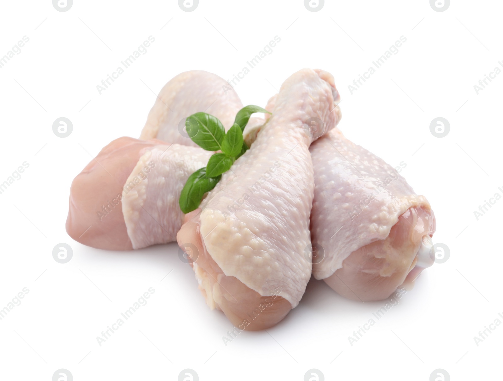 Photo of Raw chicken drumsticks with basil on white background