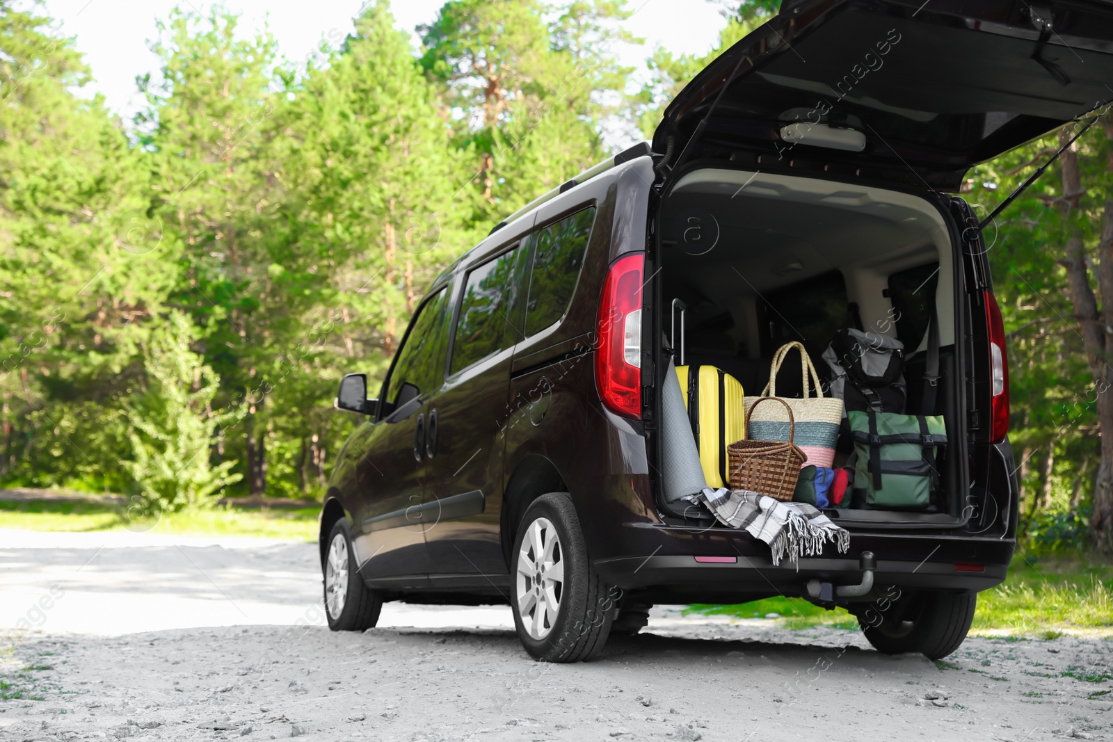 Photo of Van with camping equipment in trunk outdoors