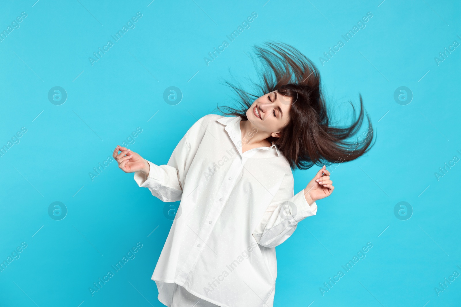 Photo of Happy woman in pyjama shaking head on light blue background